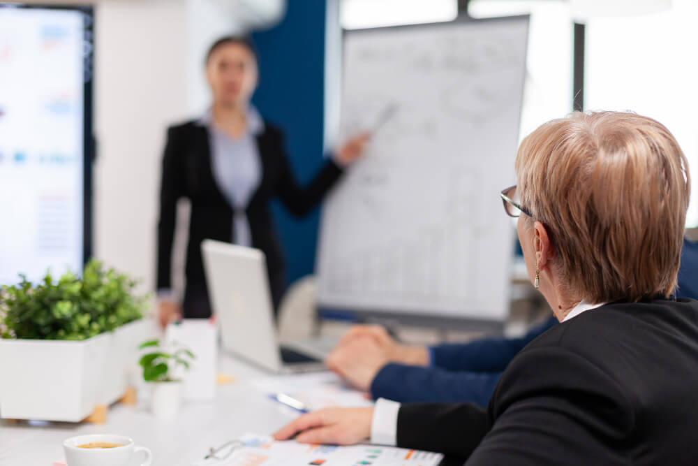 Eine Frau am Whiteboard hält ein Business Coaching ab